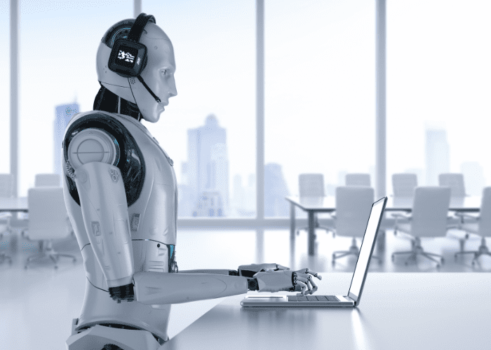 a robot sitting at a desk with a laptop